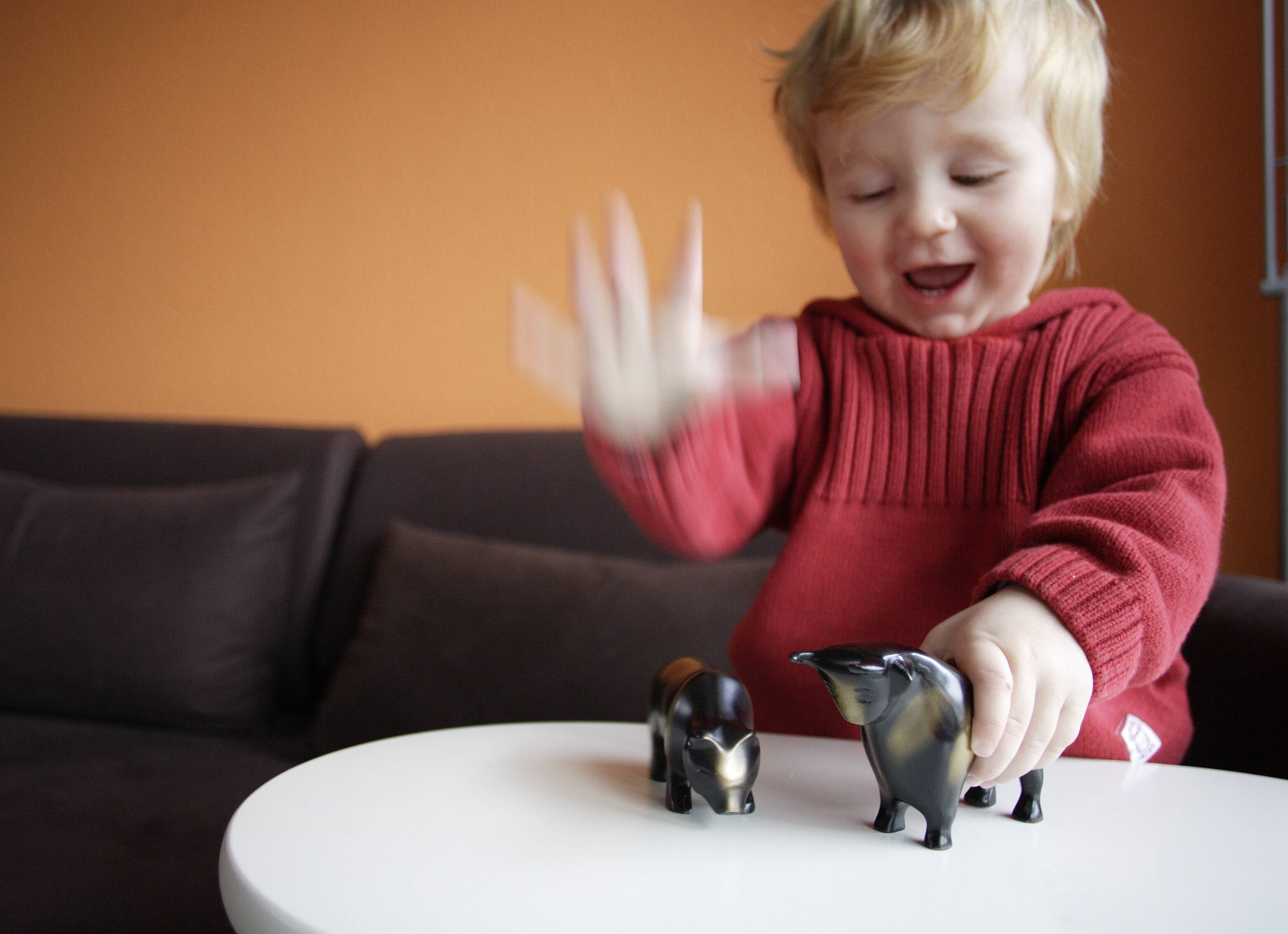 Kind spielt mit Bulle und Bär, den Symbolfiguren für das Auf und Ab an der Börse