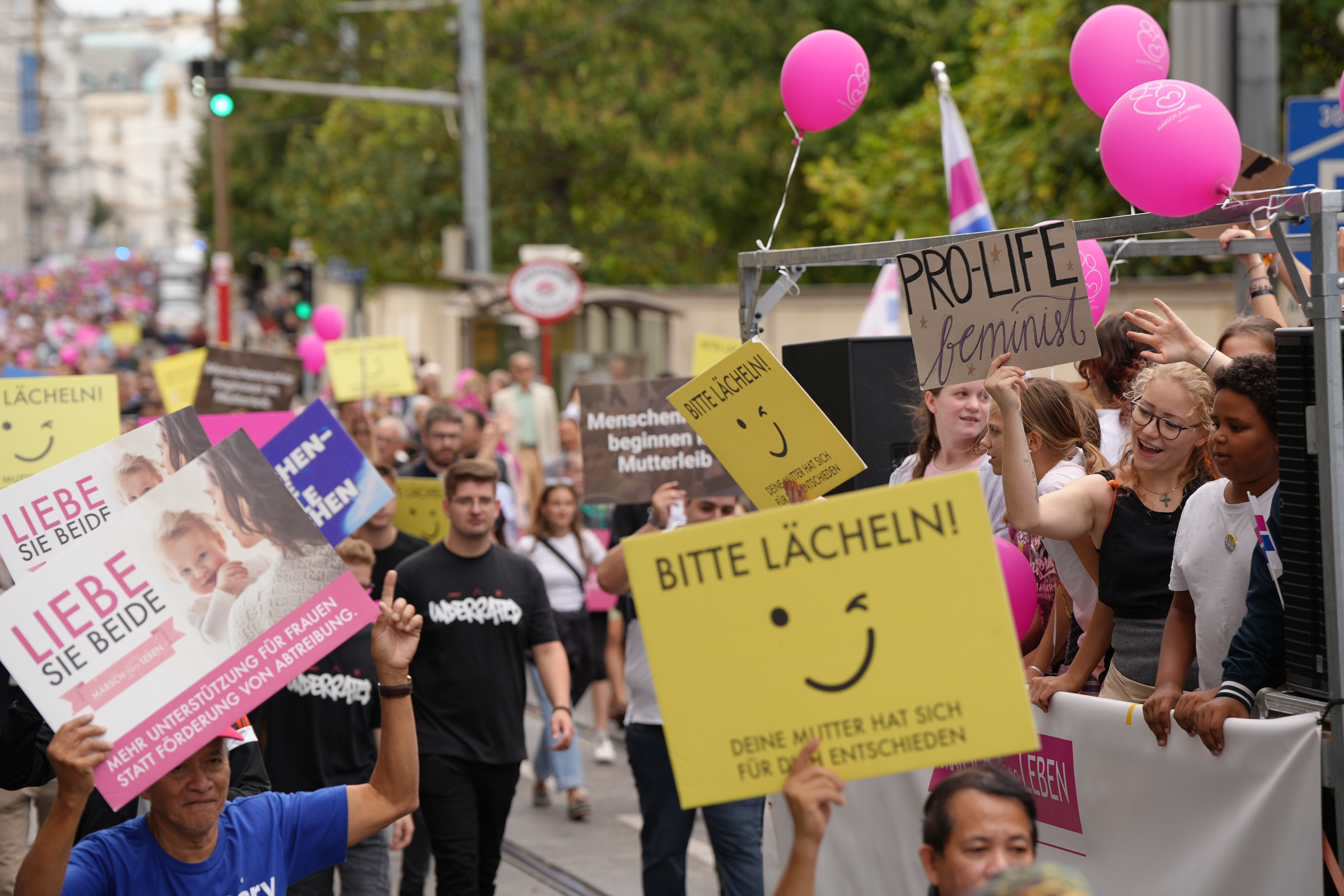 Die Teilnehmer trugen Schilder passend zur Stimmung: „Bitte lächeln! Deine Mutter hat sich für dich entschieden“ Die Teilnehmer trugen Schilder passend zur Stimmung: „Bitte lächeln! Deine Mutter hat sich für dich entschieden“