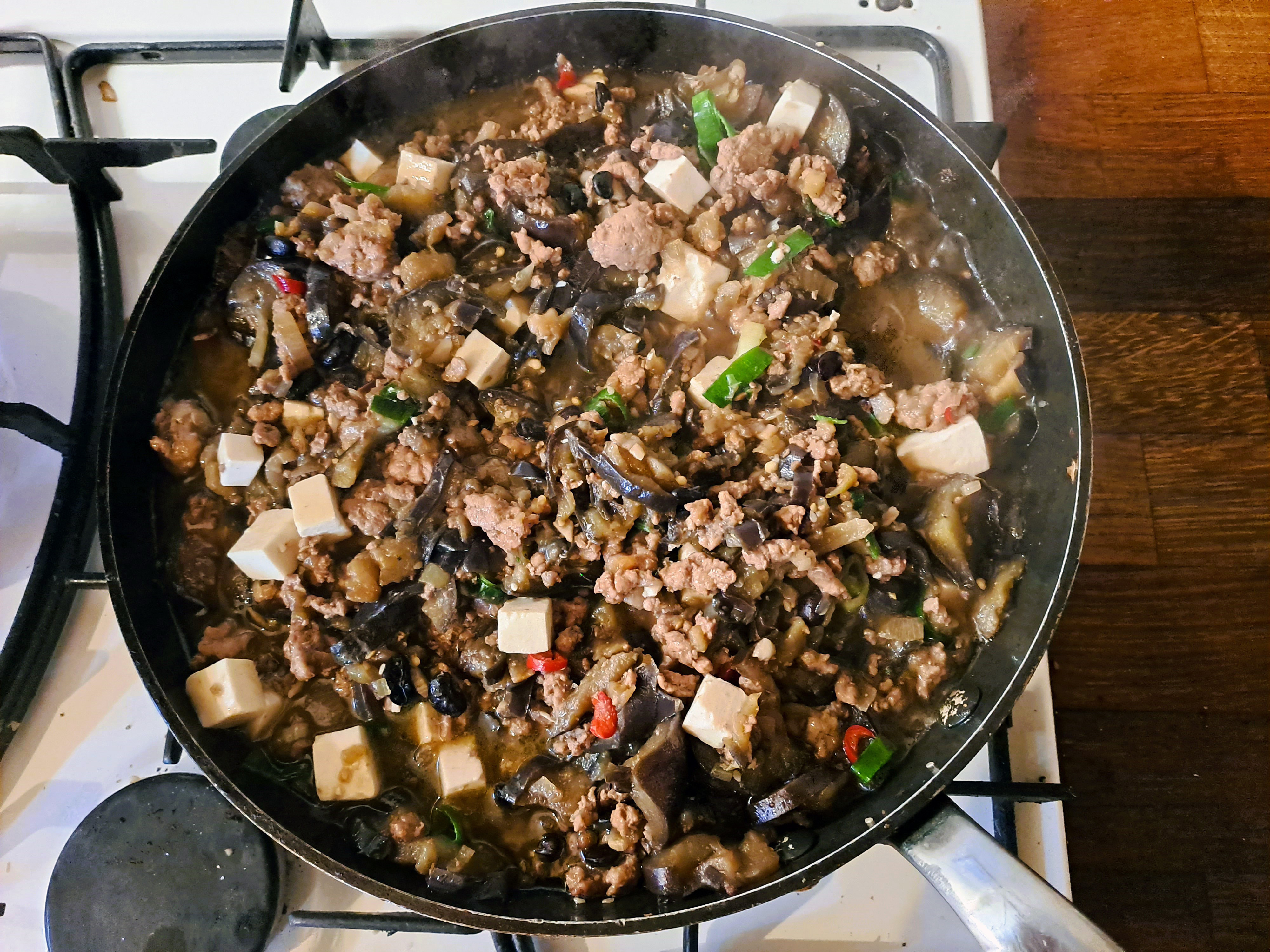 In der Pfanne: Sobald die schwarzen Bohnen sich allmählich auflösen, ist es Zeit für den gewürfelten Tofu, einen möglichst harten, ganz glatten Seidentofu, der lieblich aussieht In der Pfanne: Sobald die schwarzen Bohnen sich allmählich auflösen, ist es Zeit für den gewürfelten Tofu, einen möglichst harten, ganz glatten Seidentofu, der lieblich aussieht