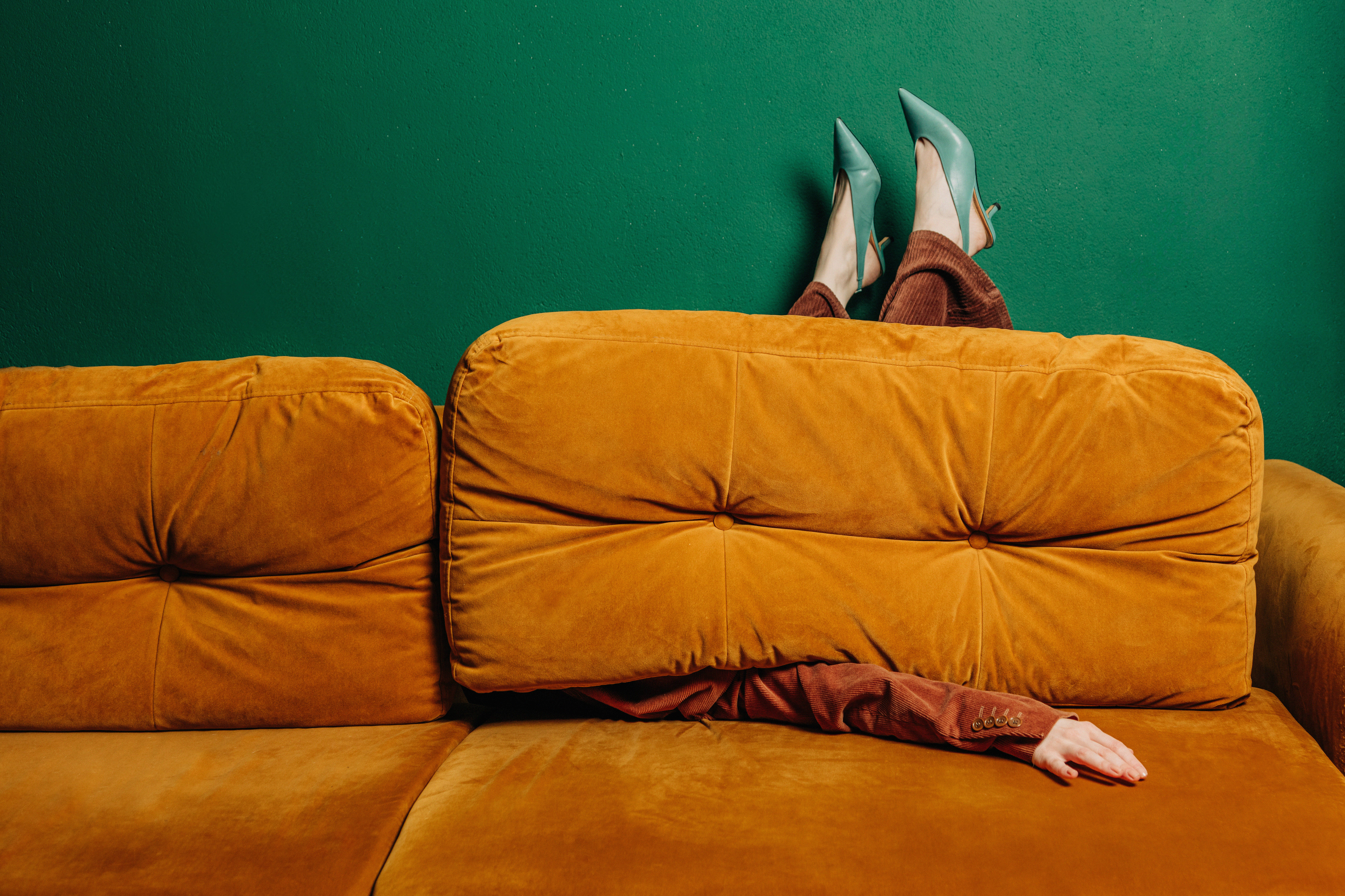 Alleinstehende schrullige Frau in hochhackigen Schuhen auf rotbraunem Sofa