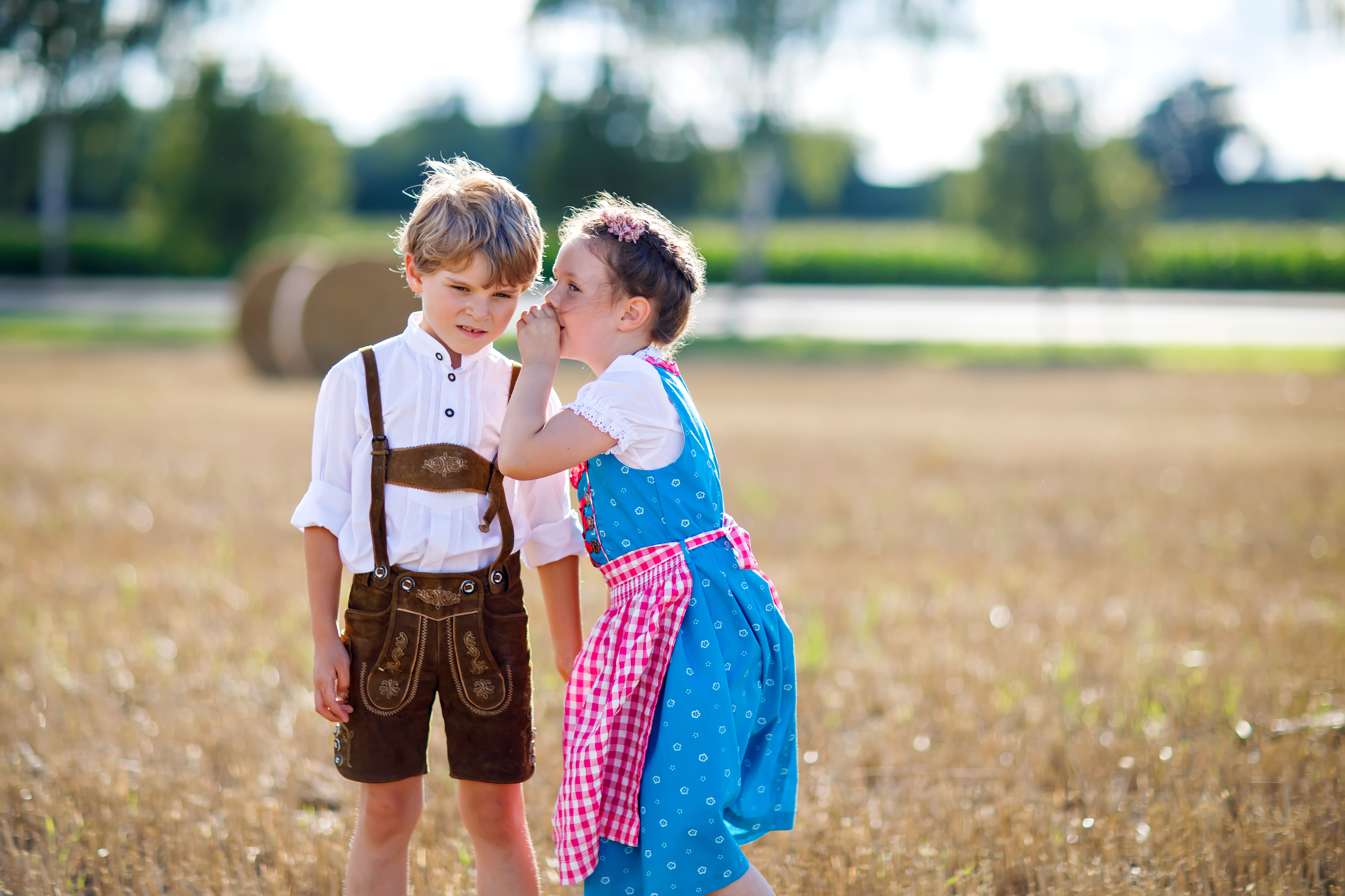 Junge und Mädchen in bayerischer Tracht auf einem Sommerfeld