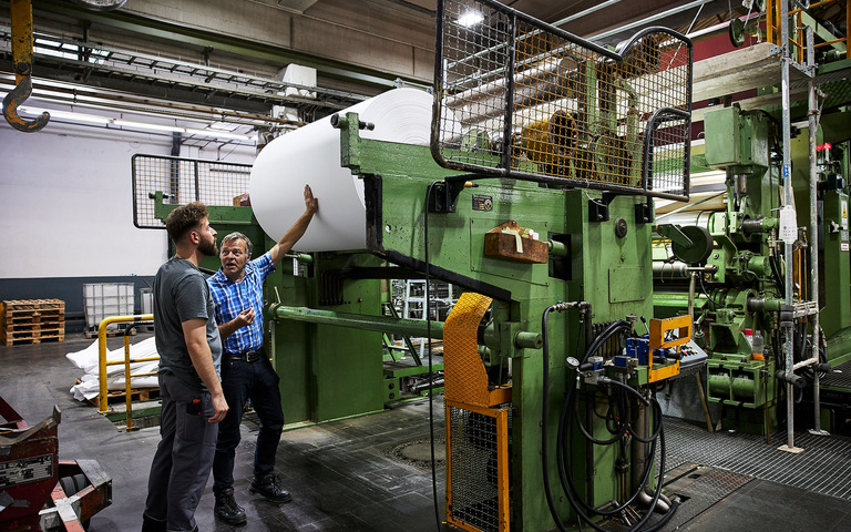Reflex-Mitarbeiter stehen an einer Papierwalze: Der Mittelstand macht vor, wie es geht