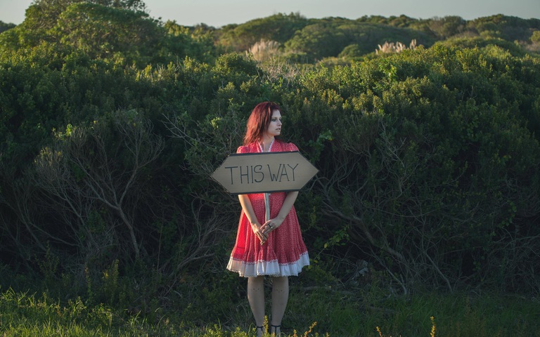 Symbolbild Entscheidung, Frau mit Schild in der Hand, unentschlossen