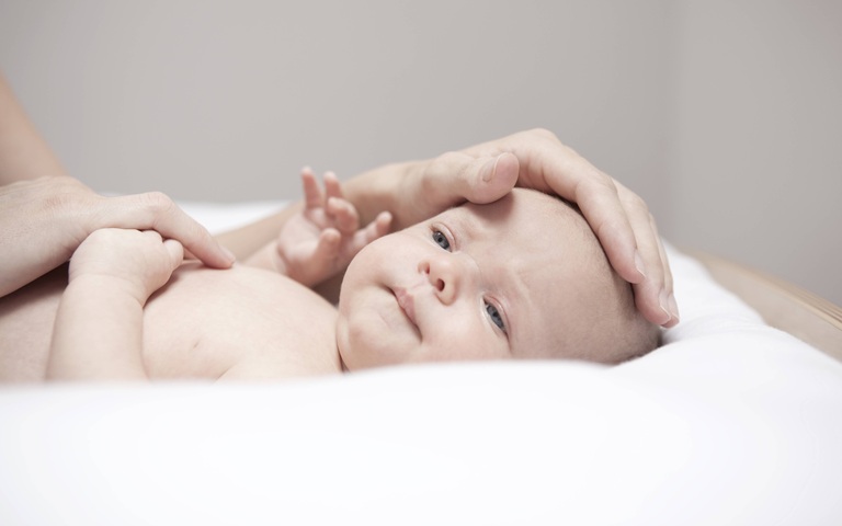 Neugeborenes Baby, beschützt von den Händen seiner Mutter