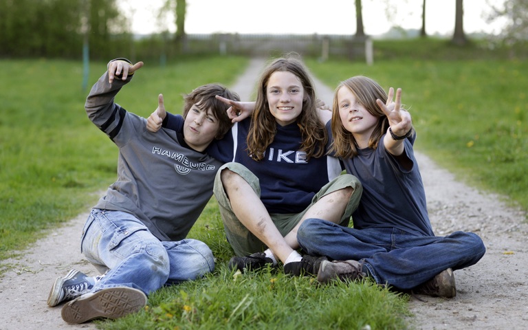 Jungs sitzen auf einem ungepflasterten Weg auf dem Dorf, Prignitz