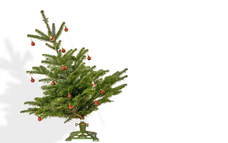 Geschmückter Christbaum auf herkömmlichem Baumständer, schiefstehend