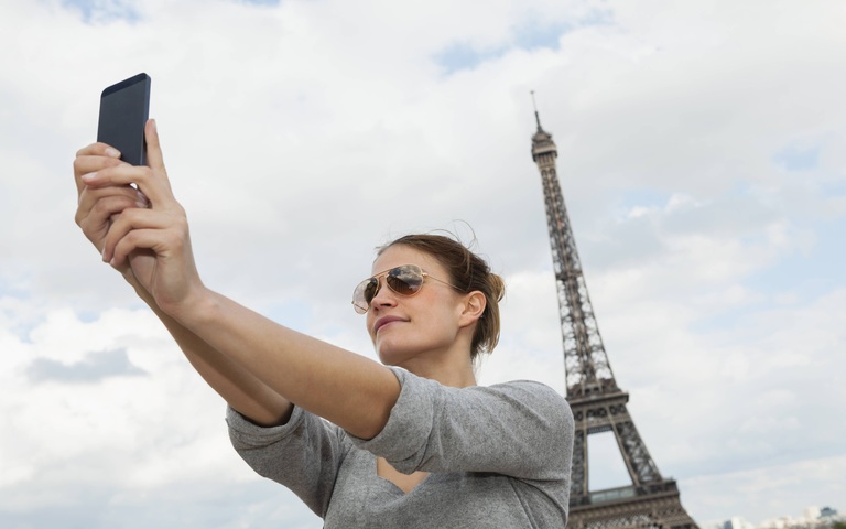 Frau macht ein Selfie vor dem Eiffelturm von sich