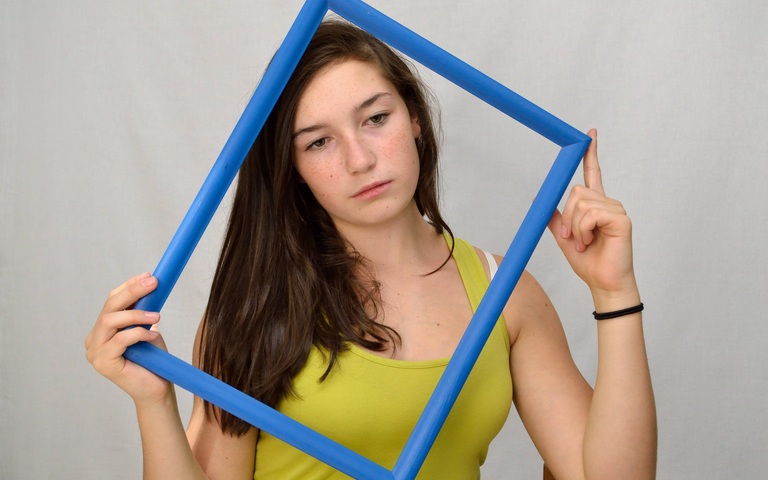 Jugendliche blickt traurig durch einen Bilderrahmen