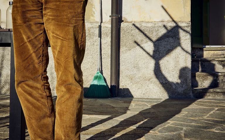 Oliver Stock in brauner Cordhose wirft einen Schatten, wie er einen Stuhl über den Kopf hält