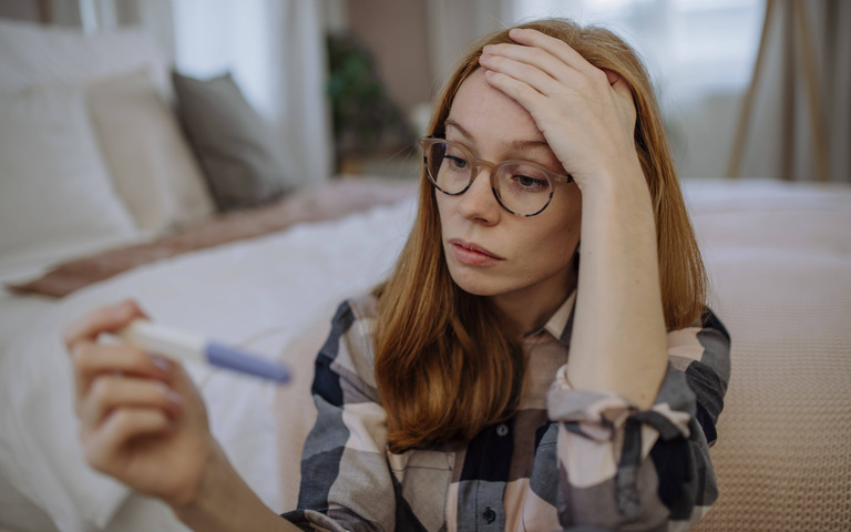 Erschrockene Schwangere mit Schwangerschaftstest (Symbolbild)