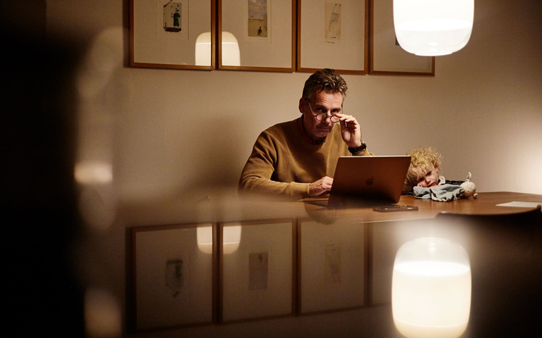 Oliver Stock zu Hause am Computer mit runder Intellektuellenbrille, Töchterchen guckt zu