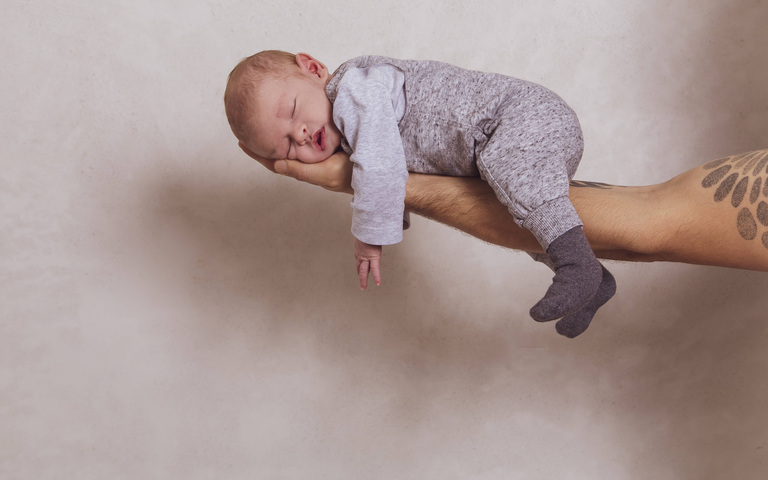 Eine starke Vaterhand trägt den schlafenden Sohn auf dem Arm, Symbolbild