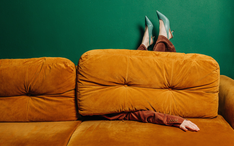 Alleinstehende schrullige Frau in hochhackigen Schuhen auf rotbraunem Sofa