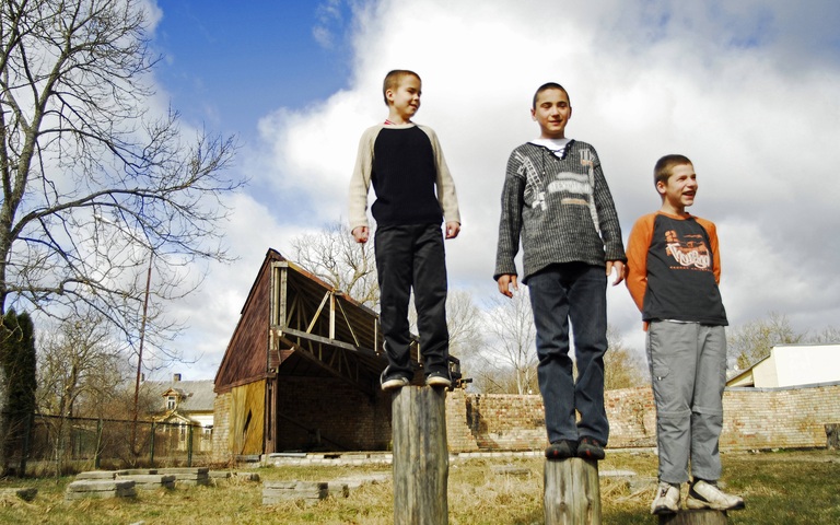 Drei Jungen stehen auf Pfählen in Jurmala, Lettland