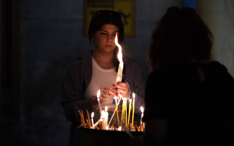 Gläubige zündet in der Grabeskirche in Jerusalem eine Kerze an