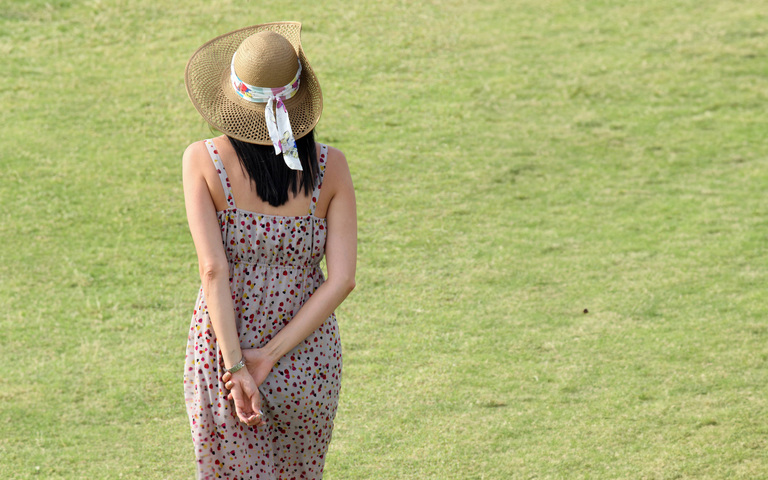 Frau schlendert mit hinter dem Rücken verschränkten Armen dahin