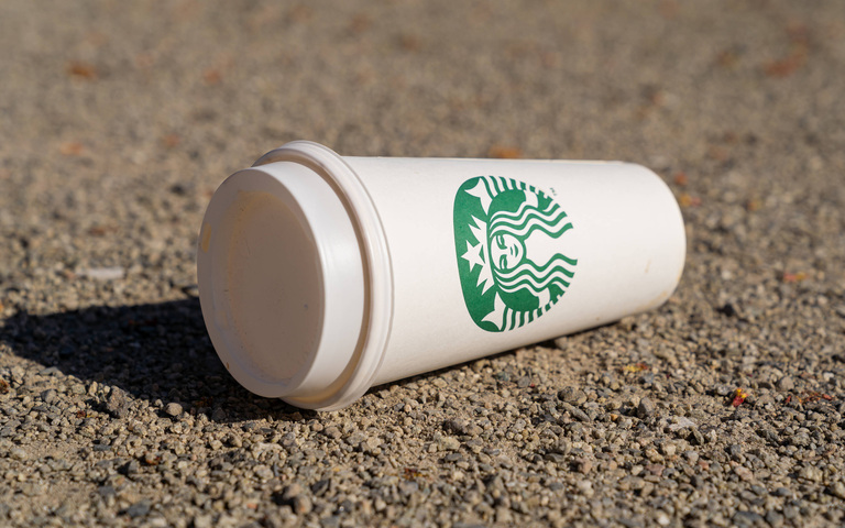 Wegwerfbecher der hochpreisigen Firma Starbucks liegt achtlos weggeworfen auf dem Boden (Symbolbild)