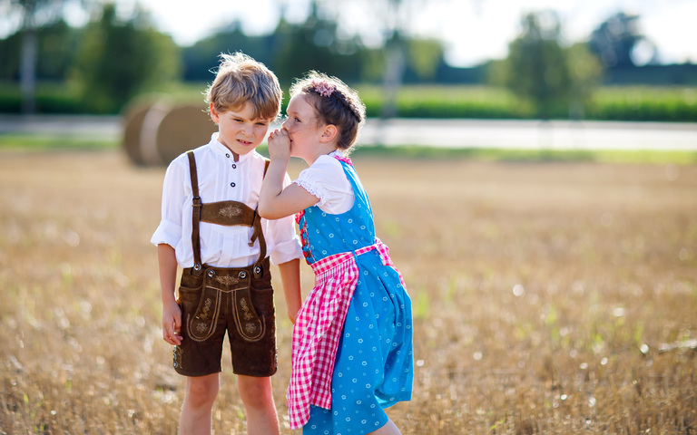 Junge und Mädchen in bayerischer Tracht auf einem Sommerfeld