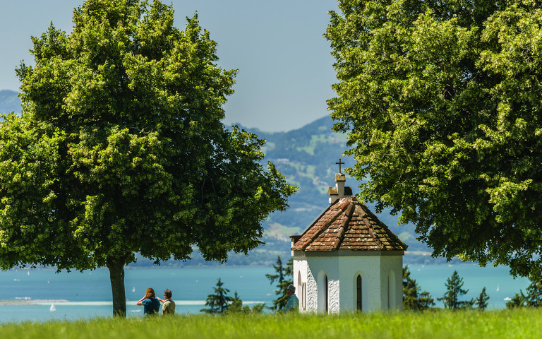 Spaziergänger besuchen die idyllisch gelegene Marienkapelle auf einer Anhöhe in Weißensberg bei Lindau am Bodensee