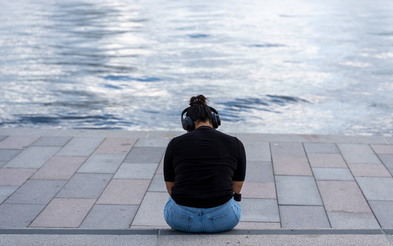 Frau mit Kopfhörern hört Musik am Meer